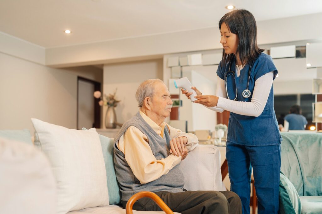 Home caregiver measuring the fever of an elderly man